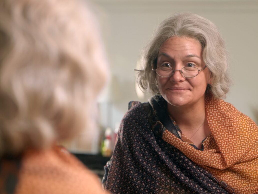 Estelle, auf alt geschminkt, schaut in den Spiegel